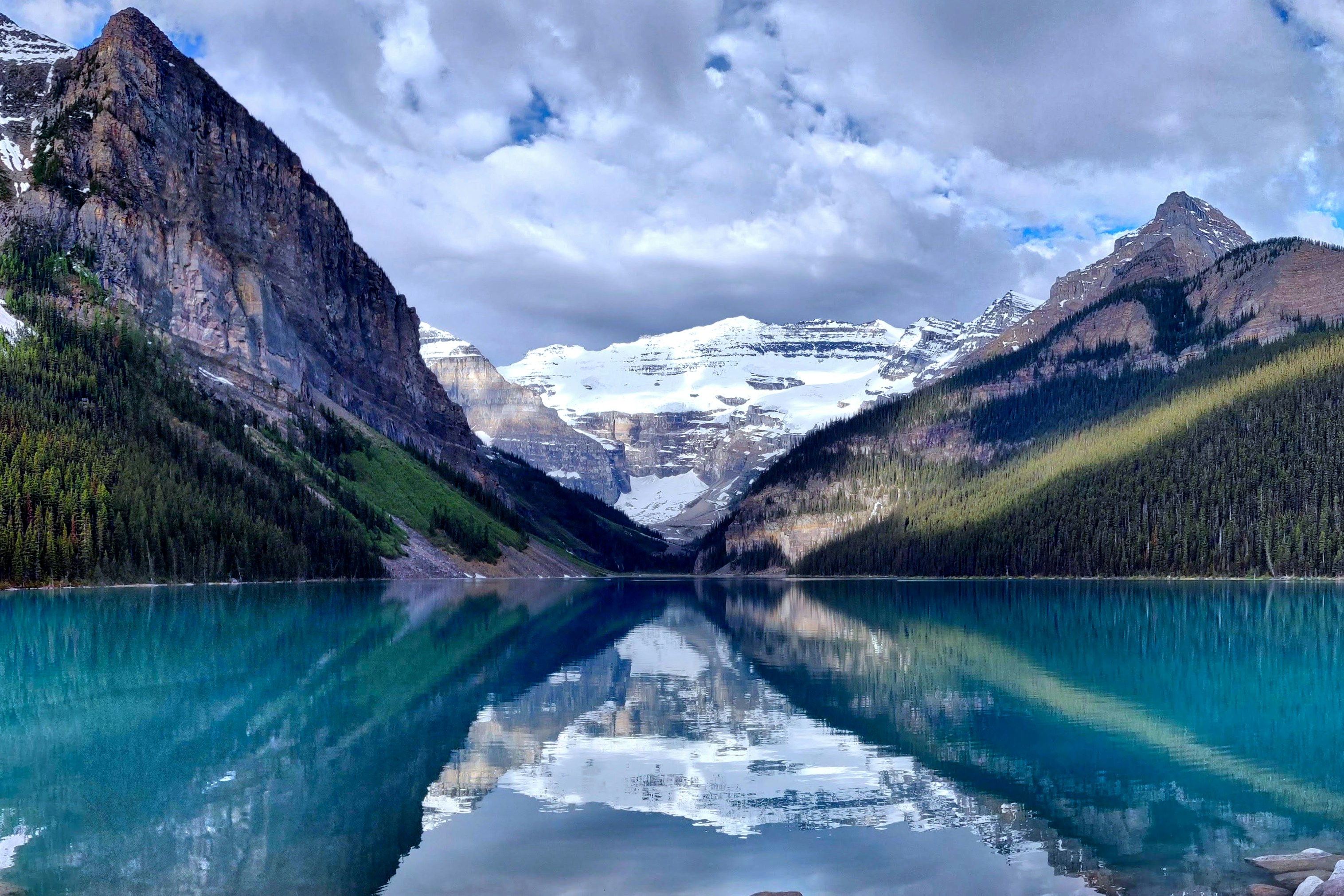 A mountain lake surrounded by forested peaks and snow-covered ridges